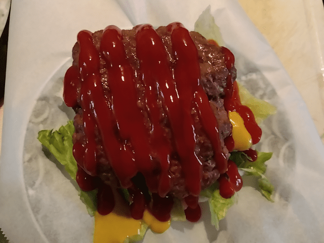 チーズハンバーガーにケチャップとお肉を乗せる画像